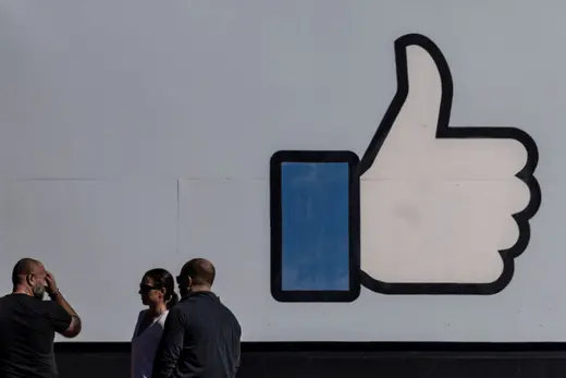 People stand in front of the entrance sign to Facebook headquarters in Menlo Park, California on October 27, 2021. 